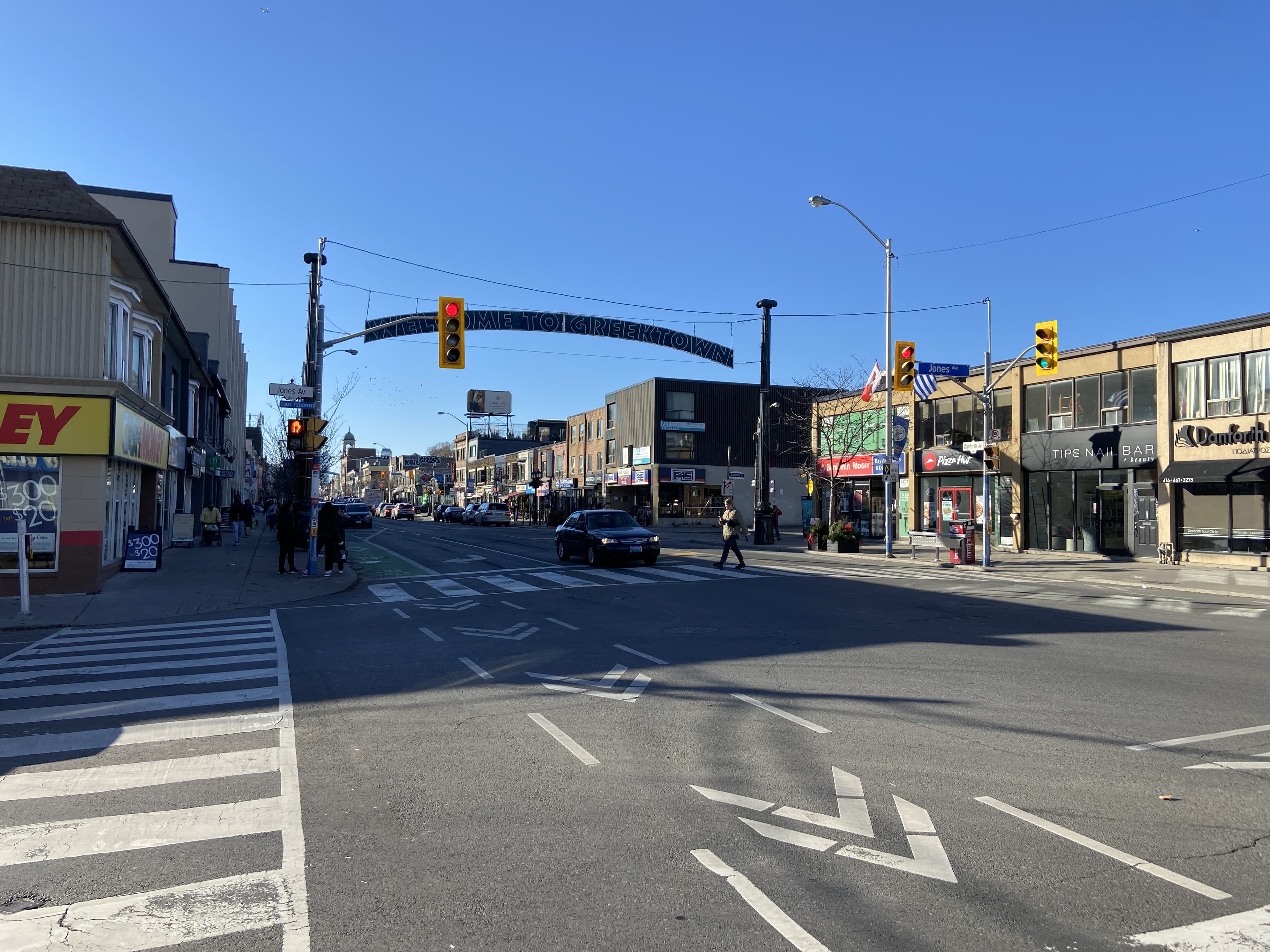 Danforth Avenue at Jones Avenue, Greektown, Toronto — main street retail and the Welcome to Greektown banner